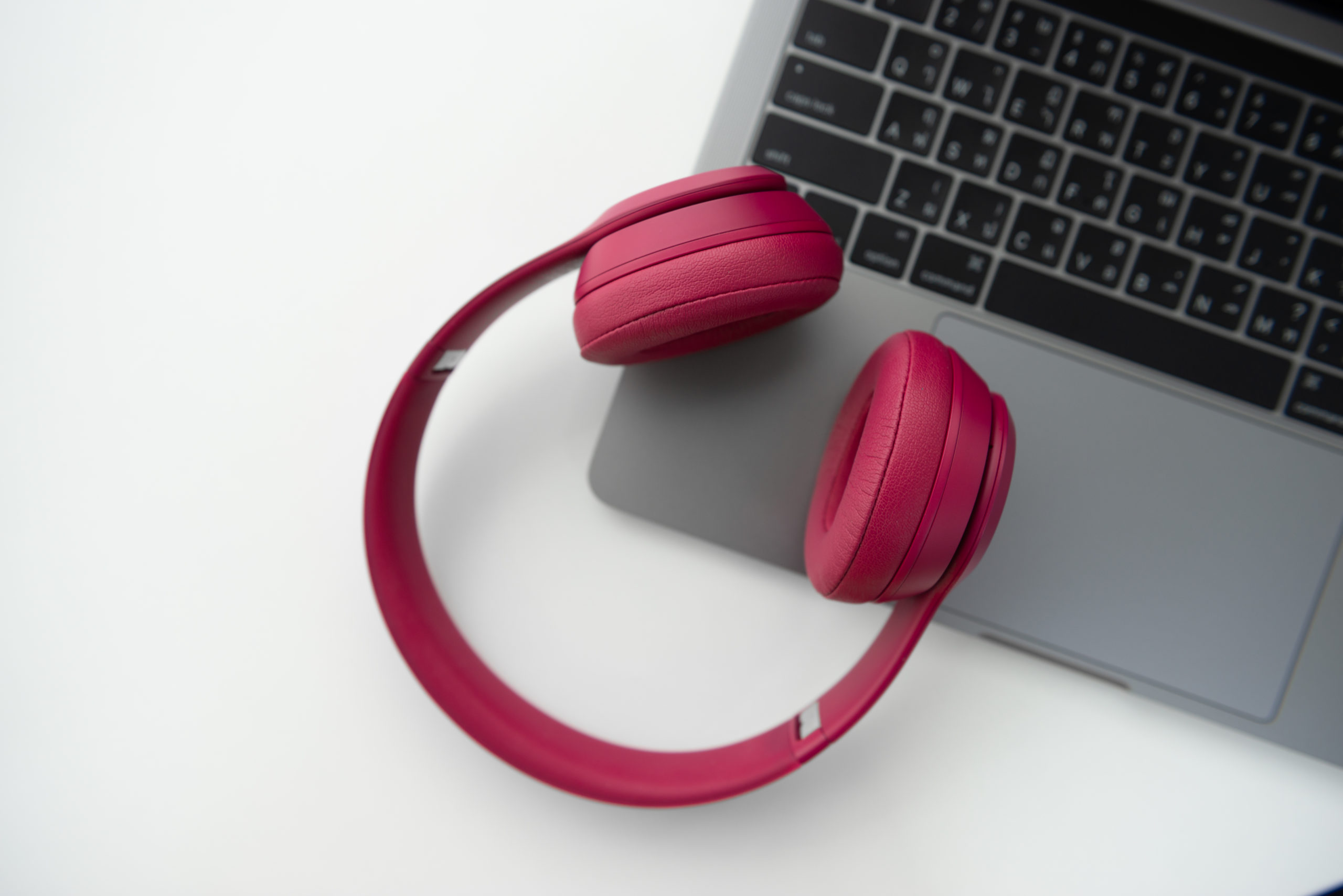 Flay lay of pink wireless headphone on the laptop keyboard